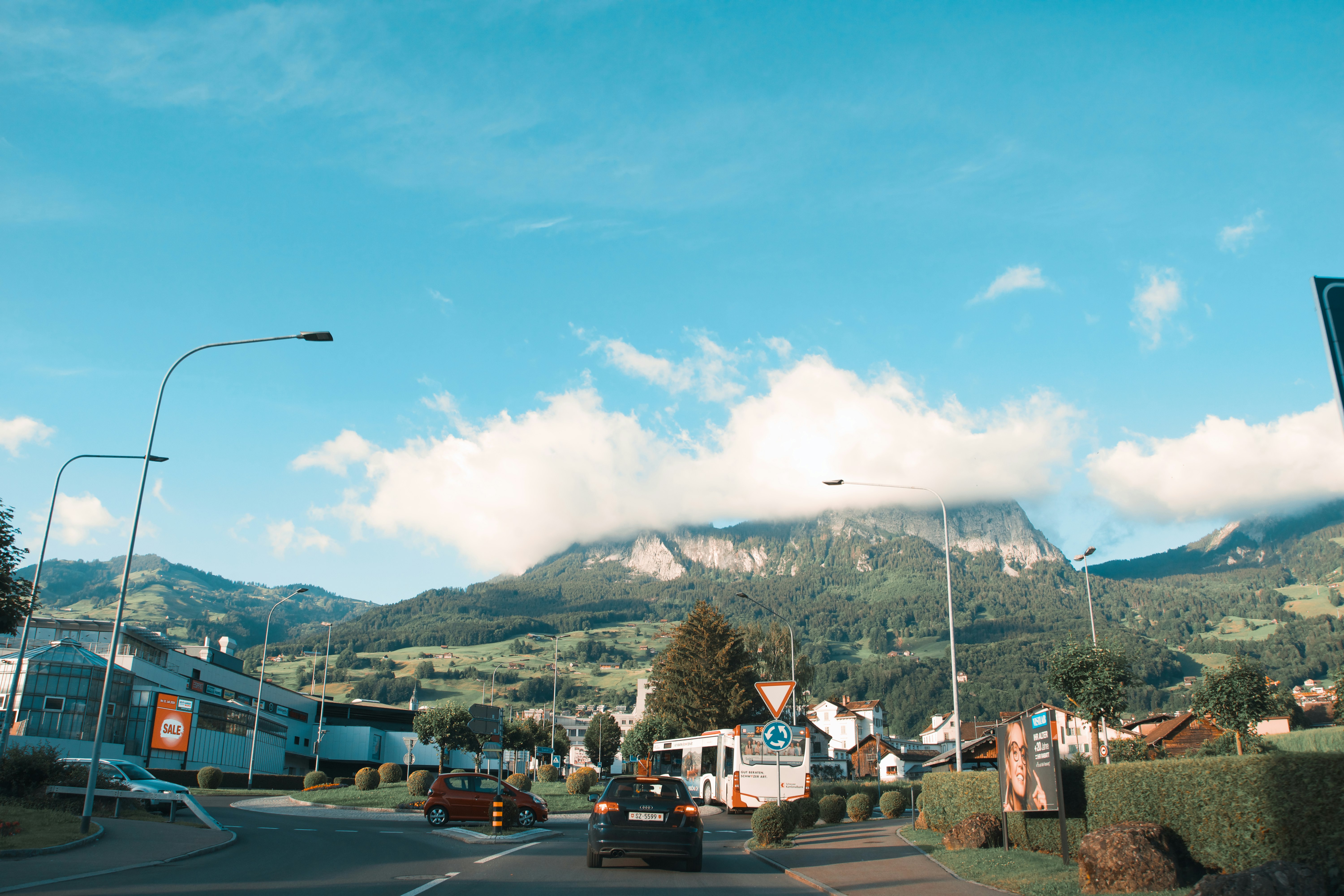 cars parked on parking lot near mountain under white clouds during daytime